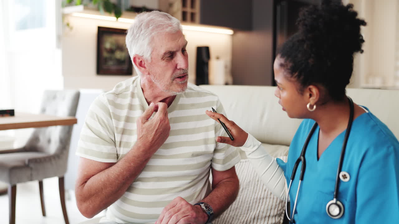 Elderly Man Discussing Symptoms with Female Nurse During Home Visit
