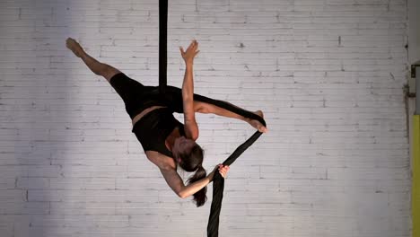 exhibición de fuerza y flexibilidad realizada por una acróbata delgada y en forma que realiza acrobacias aéreas
