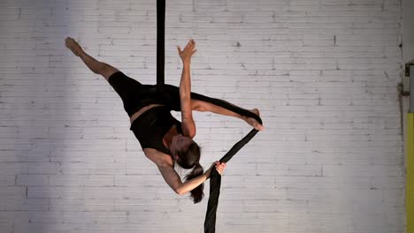 display of strength and flexibility performed by a slim and fit female acrobat performing aerial acrobatics