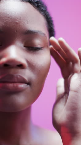 vertical video of african american woman with short dark hair in blue and pink light, slow motion