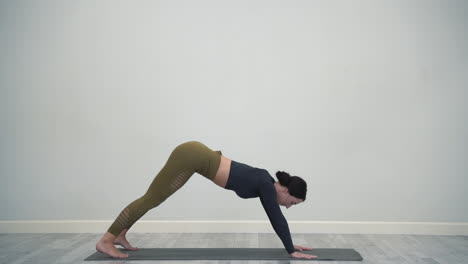 atleta femenina haciendo ejercicios de estiramiento en el interior mujer joven haciendo yoga posa hacia arriba perro