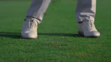 Man-legs-swinging-golf-putter-club-on-course-field.-Player-feet-stand-on-grass.