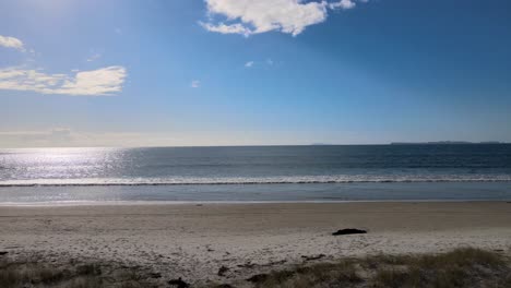 Hombre-Sentado-En-Un-Banco-Y-Disfrutando-De-Una-Relajante-Vista-A-La-Playa-De-Arena,-Horario-De-Verano