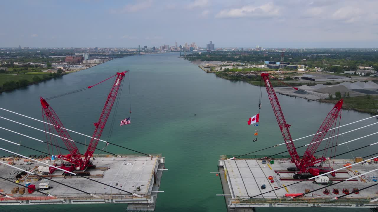 Cranes assembling the Gordie Howe International Bridge with USA and Canada flags