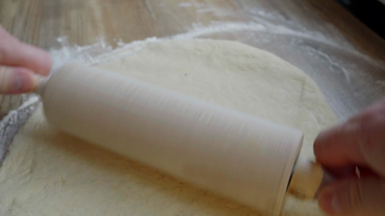 un primer plano de la masa enrollada mientras se preparan panes de trigo caseros