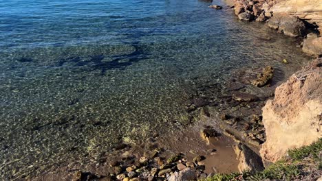crystal clear water gently washing over a rocky shoreline on crete island, greece, under bright sunlight