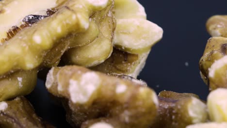 close up shot, skin of peeled walnuts rotating over black surface background