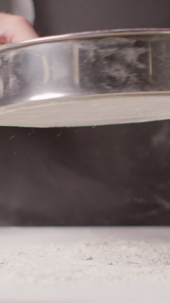 Vertical Video Overhead Shot Of Flour Being Sieved Onto Marble Work Surface For Baking