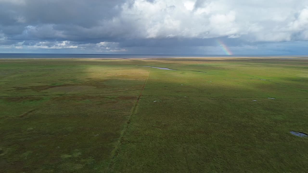 Droneoptagelse fra luften, der viser de store Skagafjordur-sletter under dramatiske skyer med åbent grønt landskab, der strækker sig mod horisonten – et islandsk landskab.
