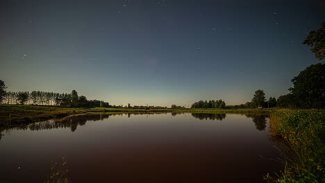 Changing-day-to-night-on-the-shore-of-a-lake-with-a-road-where-cars-drive