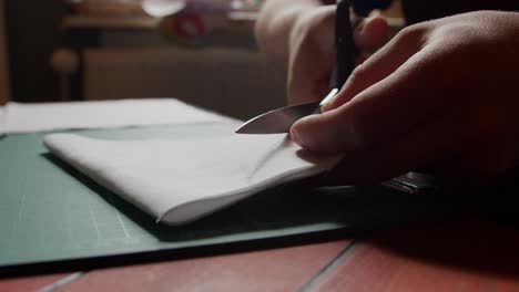 folded fabric is cut on a table with scissors.