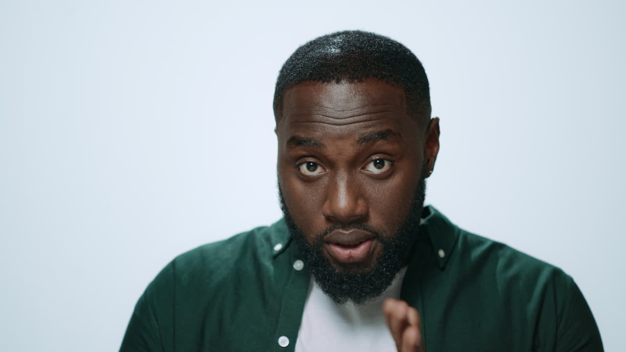 Portrait of focused african man improving appearance on grey background.
