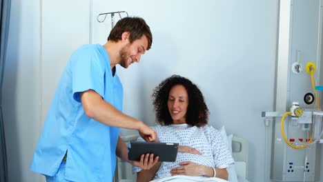 médico mostrando un informe médico a una mujer embarazada en una tableta digital