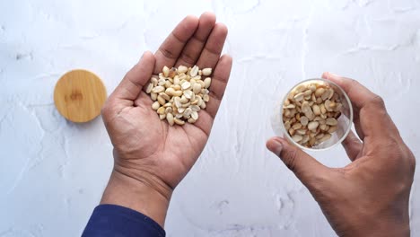 handful of peanuts and a glass jar of peanuts