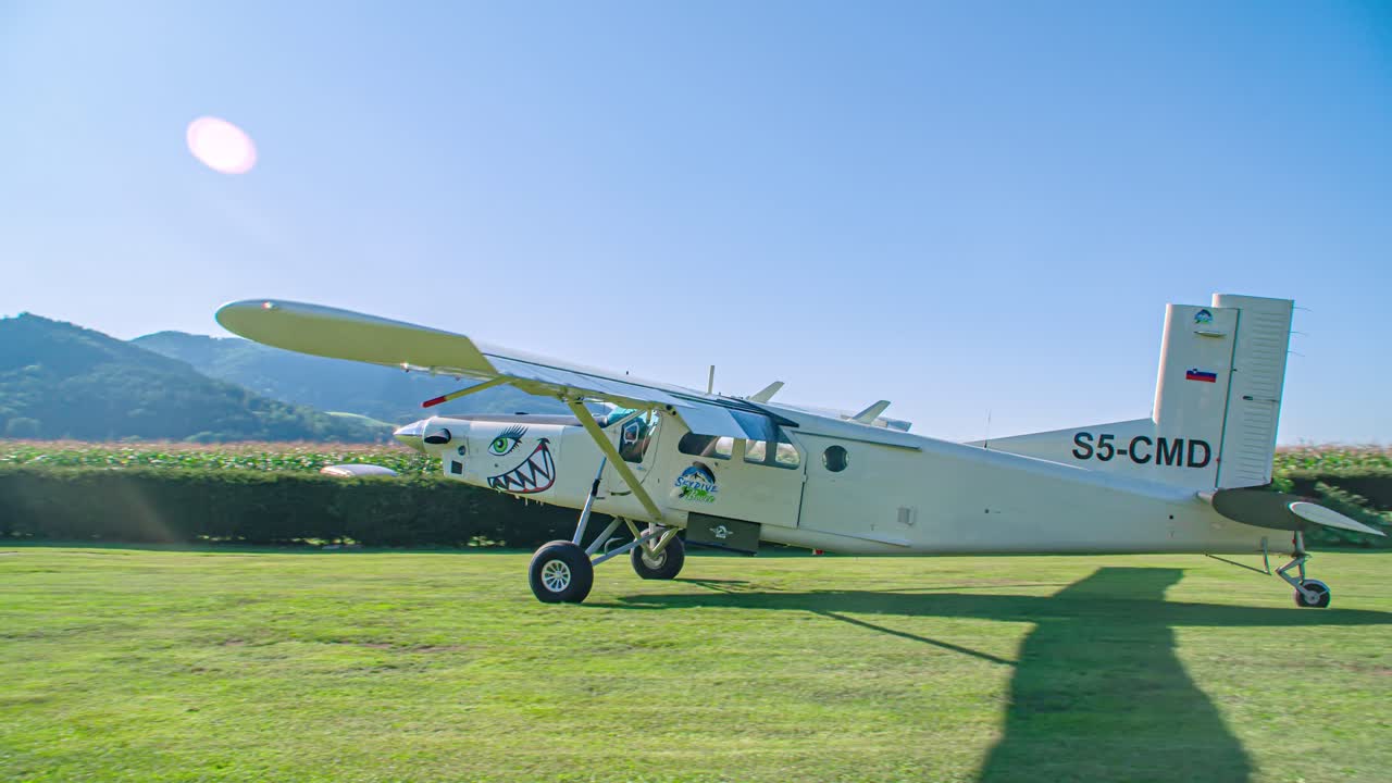 Airplane coming to a stop after landing. Skydivers on the grass with parachutes