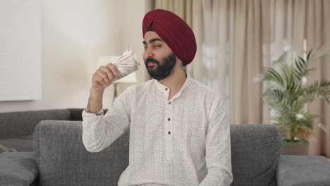 egoistic sikh indian man using money as fan