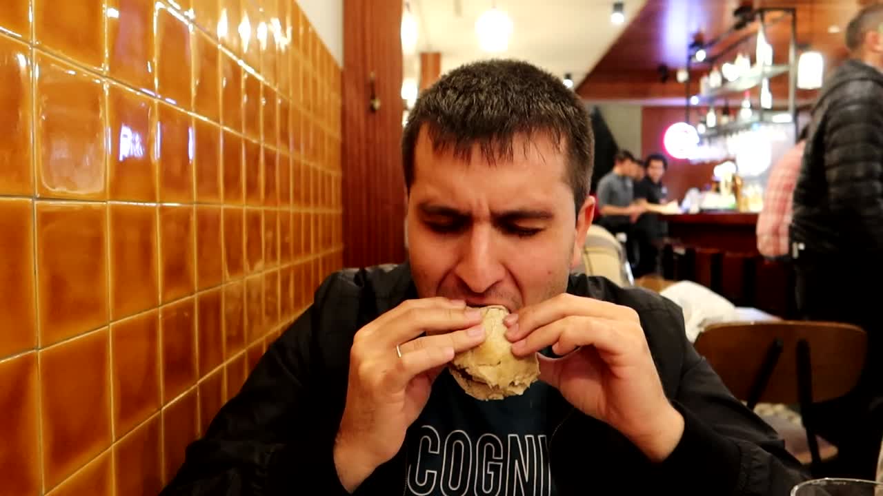 hombre comiendo un prego para cenar en un restaurante, sándwich tradicional de oporto