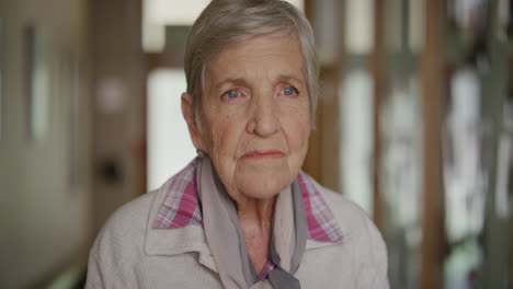 retrato de una anciana mujer caucásica de pie buscando recuerdos pensativos contemplativos en el fondo de la casa de jubilación