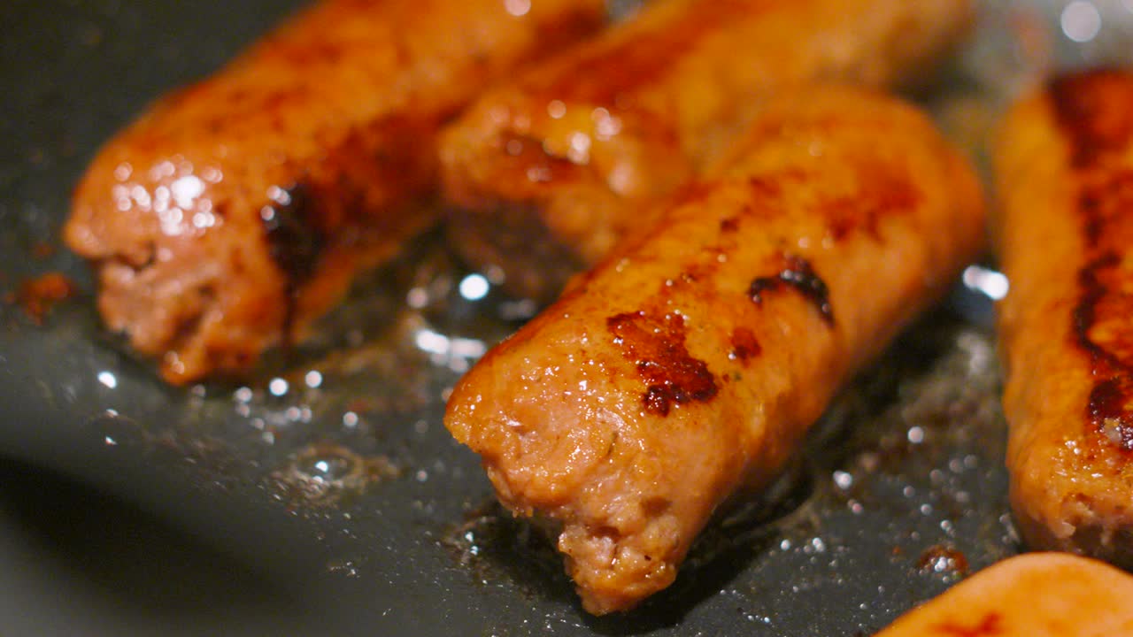 Group of Vegan Sausages Cooking in Bubbling Hot Oil Close Up. Plant Based Tasty Meatless Food. Healthier Lifestyle Choice. Slow Motion