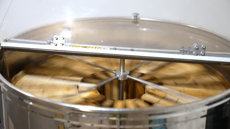 Working apparatus for extracting fresh honey. Rotating mechanism inside the metal bin full of honey frames.