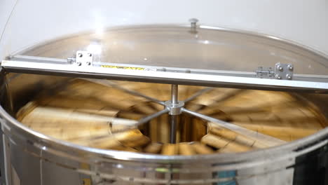 working apparatus for extracting fresh honey. rotating mechanism inside the metal bin full of honey frames.