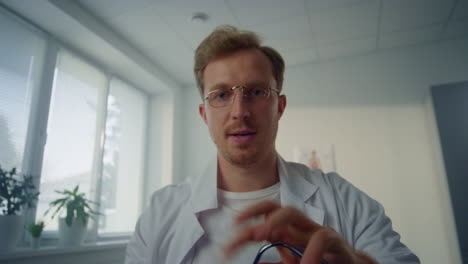 un médico con un estetoscopio revisando los pulmones de un paciente en un video de pov de una clínica moderna.