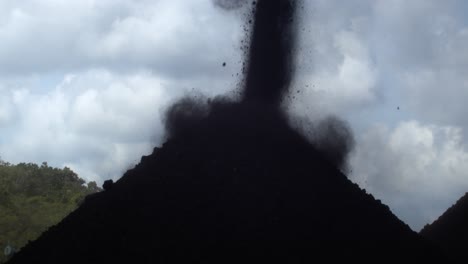 movimento lento di carbone schiacciato cadere in mucchio con nube drammatica sullo sfondo