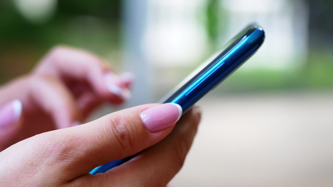 una mujer está sentada en un café con un teléfono inteligente en las manos con una maqueta de pantalla verde. la chica utiliza activamente el teléfono para sus propios propósitos. contenido, videos, blogs.