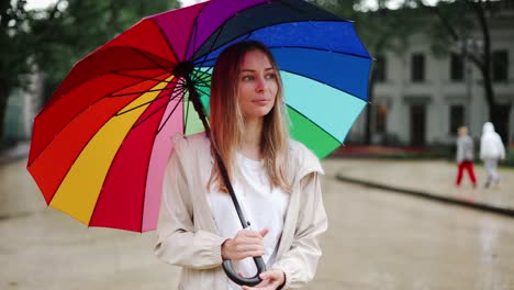 Retrato-De-Una-Mujer-Girando-Un-Paraguas-Multicolor-En-La-Calle