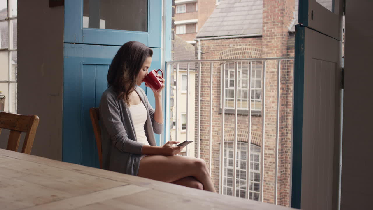 café de la mañana para mujer de raza mixta usando teléfono inteligente en casa en pijama