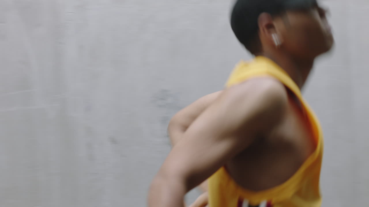 uomo che balla giovane ballerino di strada felice che esegue vari movimenti di danza freestyle uomo di razza mista che si esercita in un magazzino grungy che indossa un giubbotto giallo da vicino