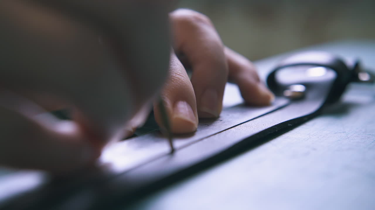 un abile sarto disegna un punto su una striscia di tessuto di pelle nera