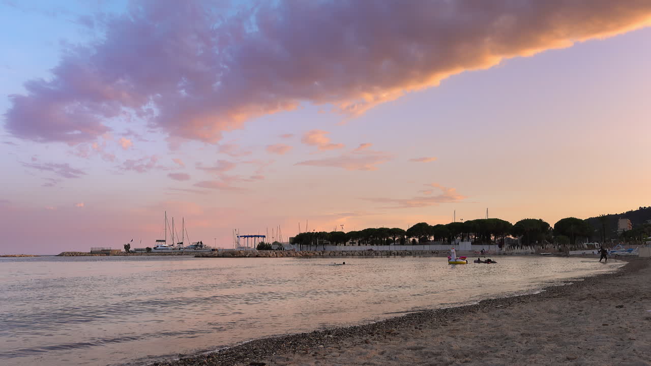 People playing and relaxing on the beach at sunset in Cannes, France