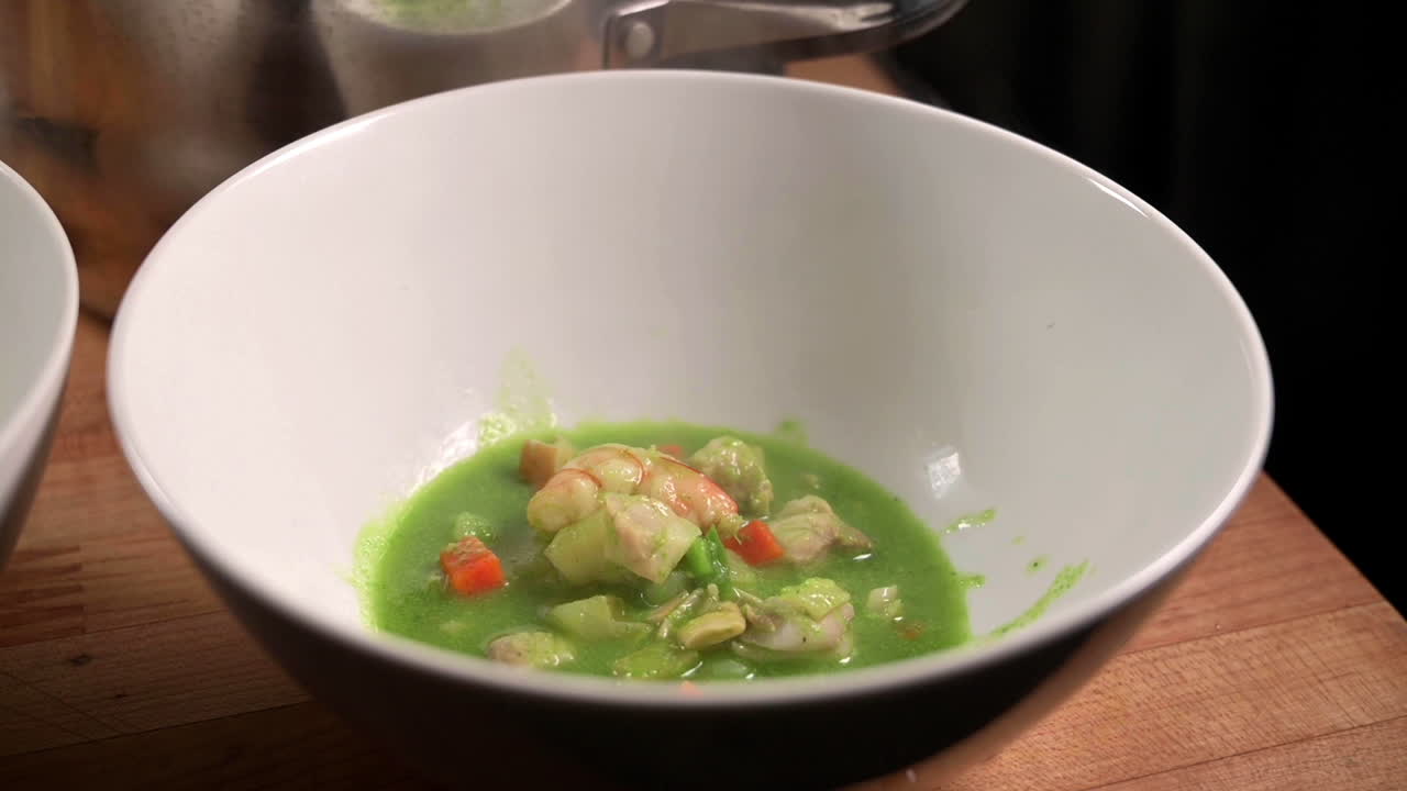 sirviendo una sopa de mariscos de cilantro peruano recién cocinada en un tazón blanco