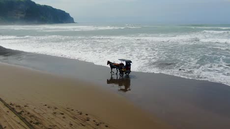 Aerial,-traditional-Javanese-horse-carriage-on-Parangtritis-beach,-Indonesia