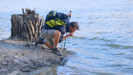 male hiker drinking water from river 4k