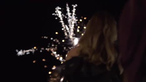 primer plano de una mujer joven y atractiva viendo un espectáculo de fuegos artificiales en la oscuridad