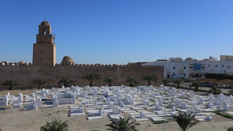 mezquita histórica con altísimo minarete y cementerio bajo un cielo azul claro en túnez