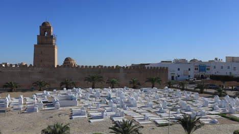 historic mosque with towering minaret and cemetery under a clear blue sky in tunisia