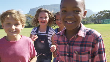 Five-friends-running-towards-camera-in-a-park,-front-view