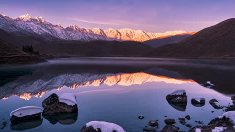 alpenglow on snow-capped mountains reflected in a serene lake