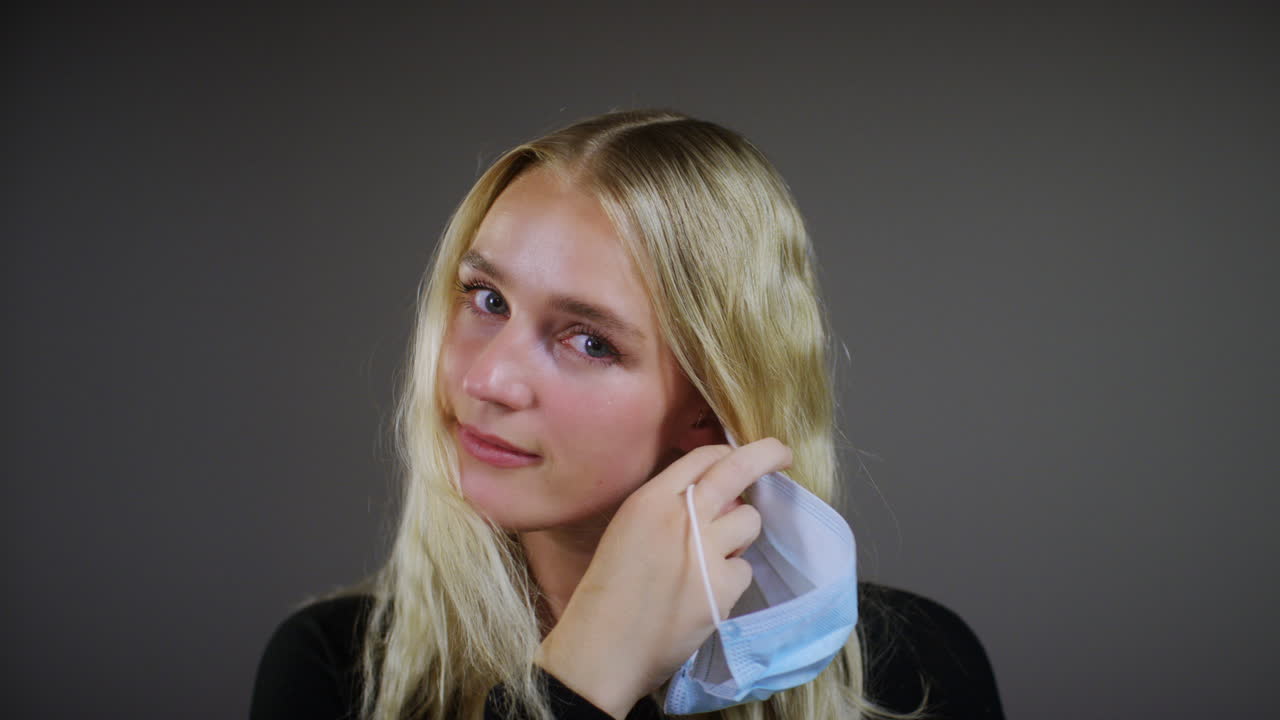 젊은 금발의 여자는 얼굴 마스크 미소를 제거합니다