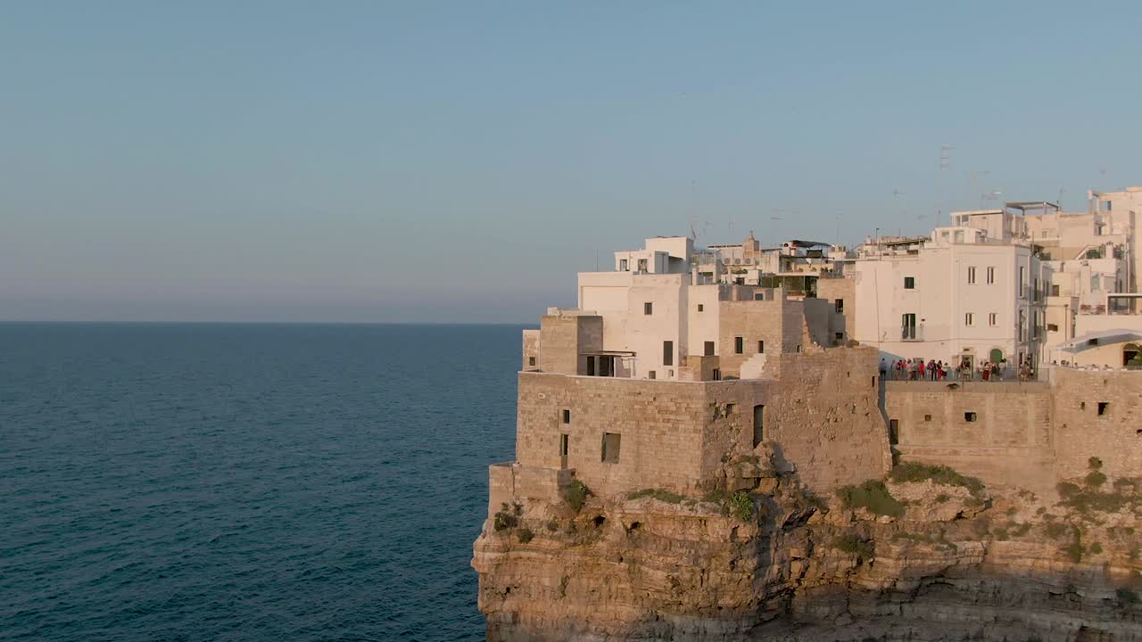 hermosa toma aérea de drones a la hora dorada en polignano una yegua que muestra la ciudad en los acantilados con el mar y el cielo azul, increíble ciudad italiana antigua al atardecer en la región de apulia en el sur de italia