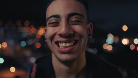 portrait attractive young arab man on rooftop at night smiling happy enjoying urban nightlife with bokeh city lights in background