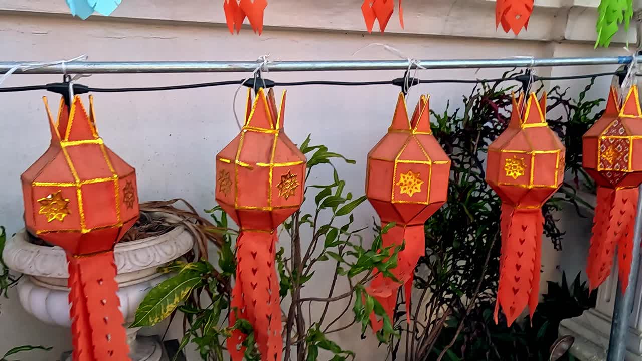 Handheld motion dolly right to rows of traditional Lanna lantern or Khom Pet decorating a wall beside the streets of Chiang mai, Thailand