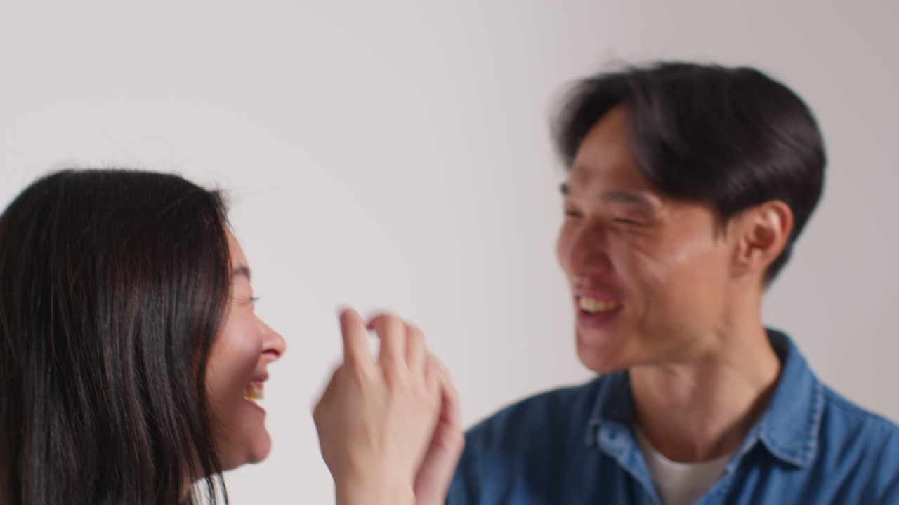 색 스튜디오 배경 앞의 젊은 친구 그룹이 사진 부스 스타일의 초상화를 위해 포즈를 취하고 있습니다.