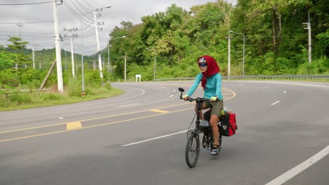 asian woman cycling on the highway on a trip through southeast asia