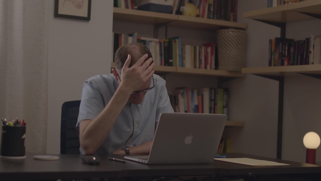 A man in an office talking on a virtual call on his laptop. He speaks on the call and ends it, shutting his laptop