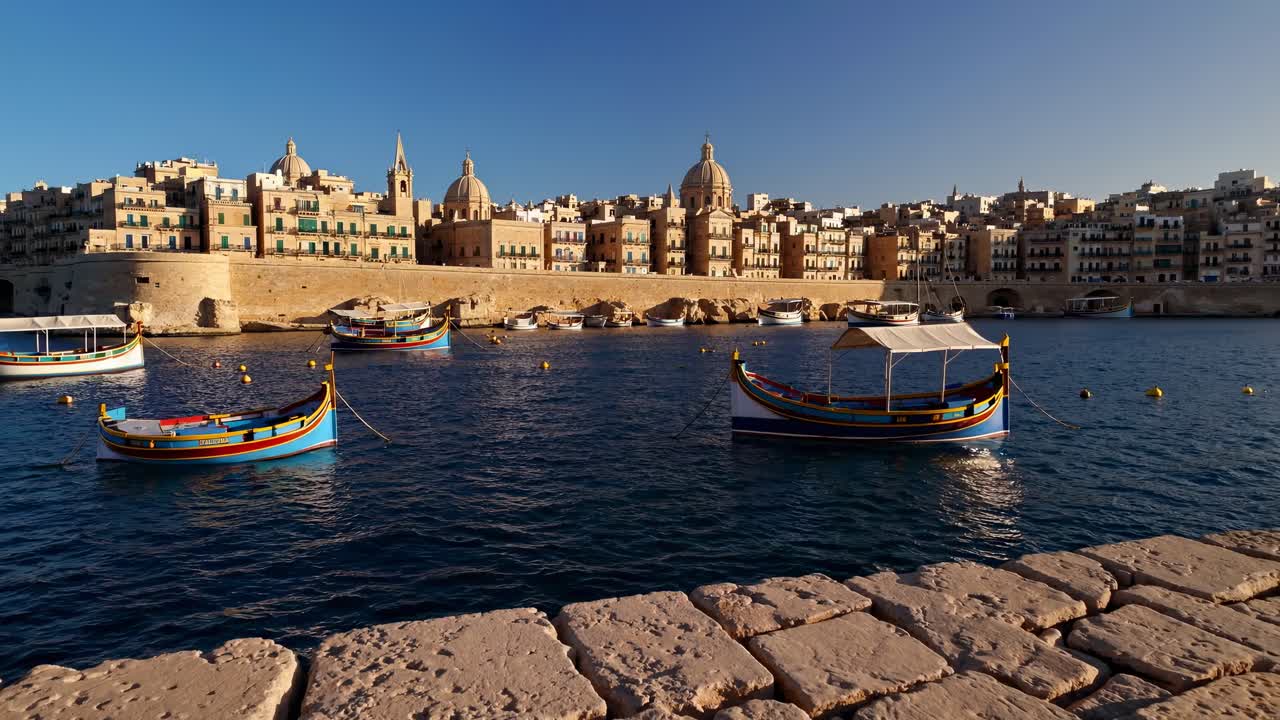Wide-angle video capturing colorful boats on calm water with historic buildings in the background