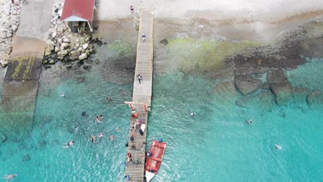 Playa-piskado-in-curacao-with-colorful-beach-umbrellas-and-boats,-aerial-view